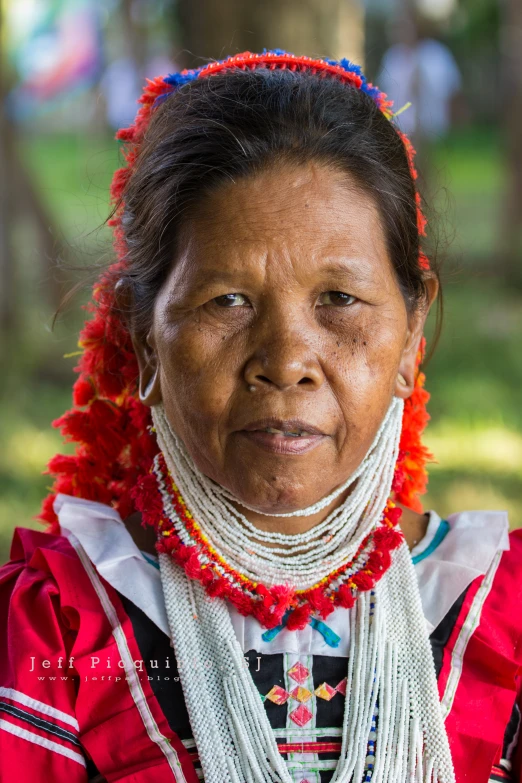 a women in a red and white native garb looks into the camera