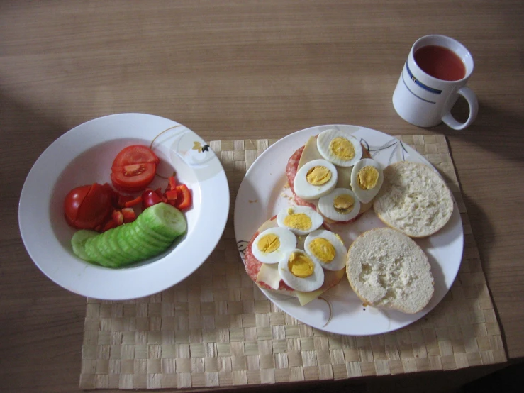 plate with eggs, pickles, tomatoes and pickles next to cup