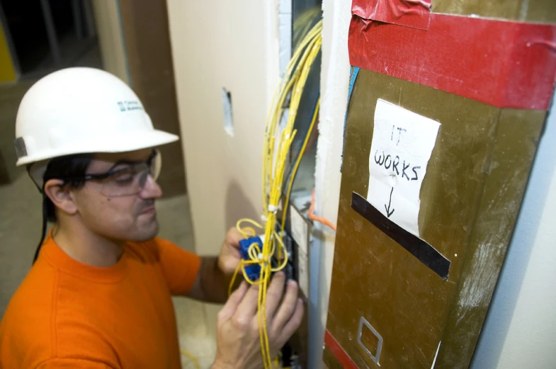 a man wearing a hard hat working on a light switch