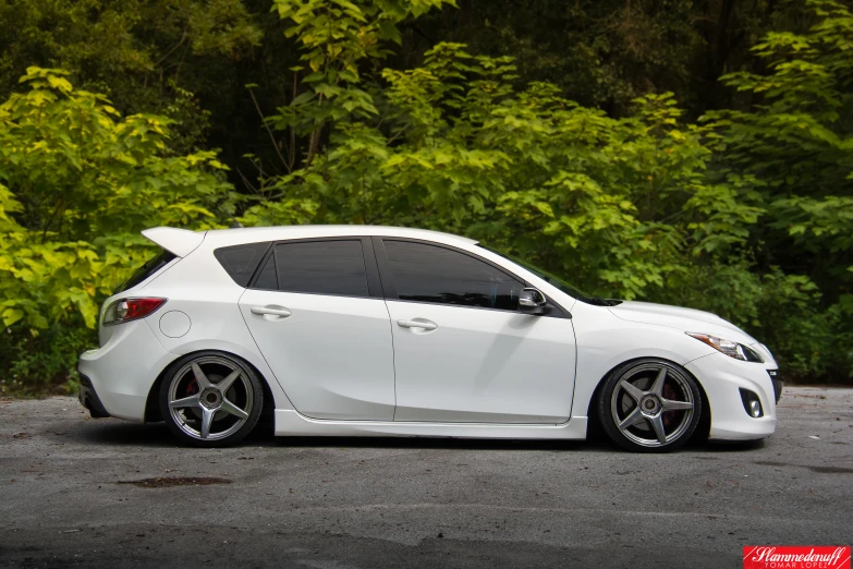 a white car with black wheels is parked on the road