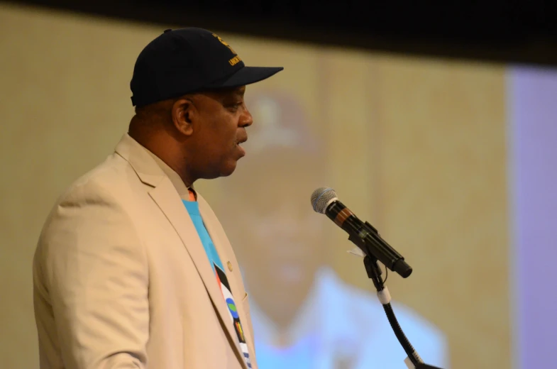 a man in a blue cap speaks into a microphone