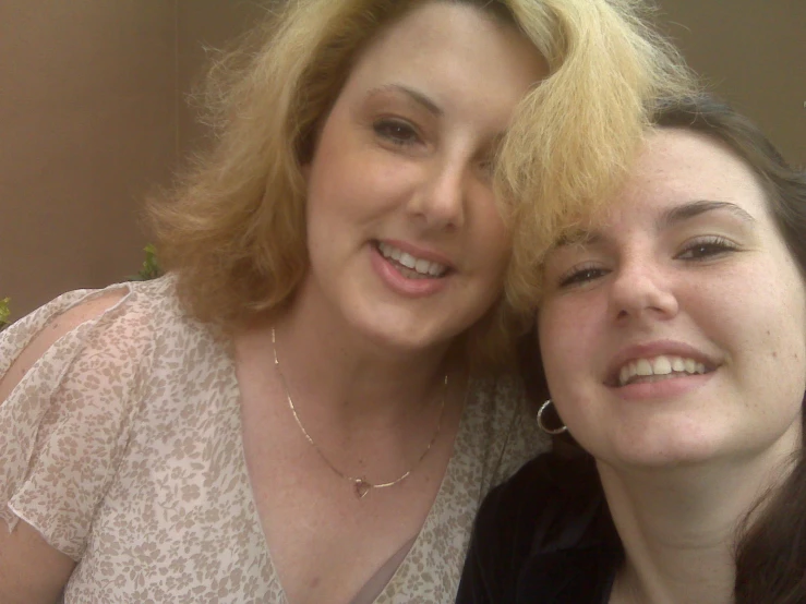 two ladies smile for the camera while they pose for a picture