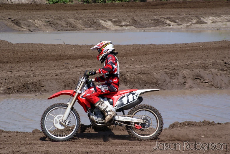 a motorcyclist is parked at the edge of a muddy river