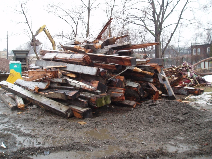 man is lifting out wood from piles on a street