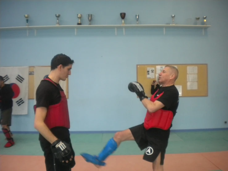 two men in black shirts and red shorts standing on blue mat