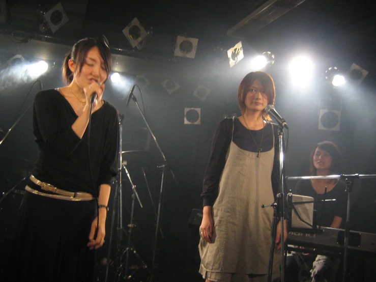 two women are singing into microphones on stage