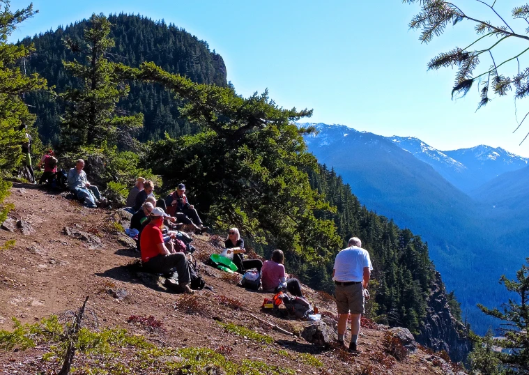 people are sitting at the top of the mountain with mountains