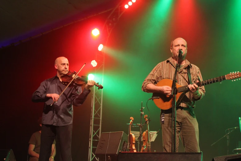 a man standing next to a man with a guitar on stage