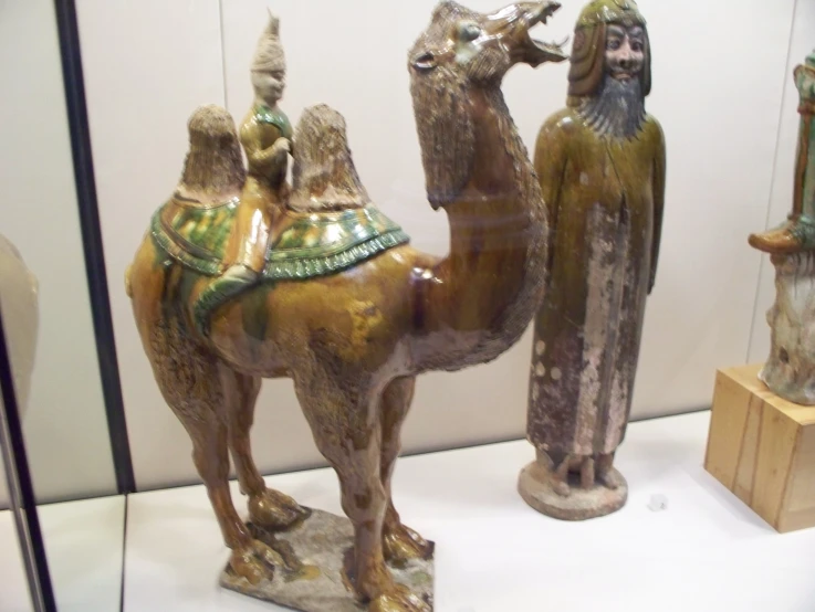 several statues are in the glass case, each holding a camel