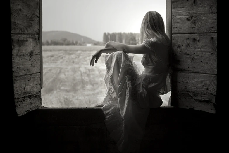 a woman wearing a dress looking out of a window