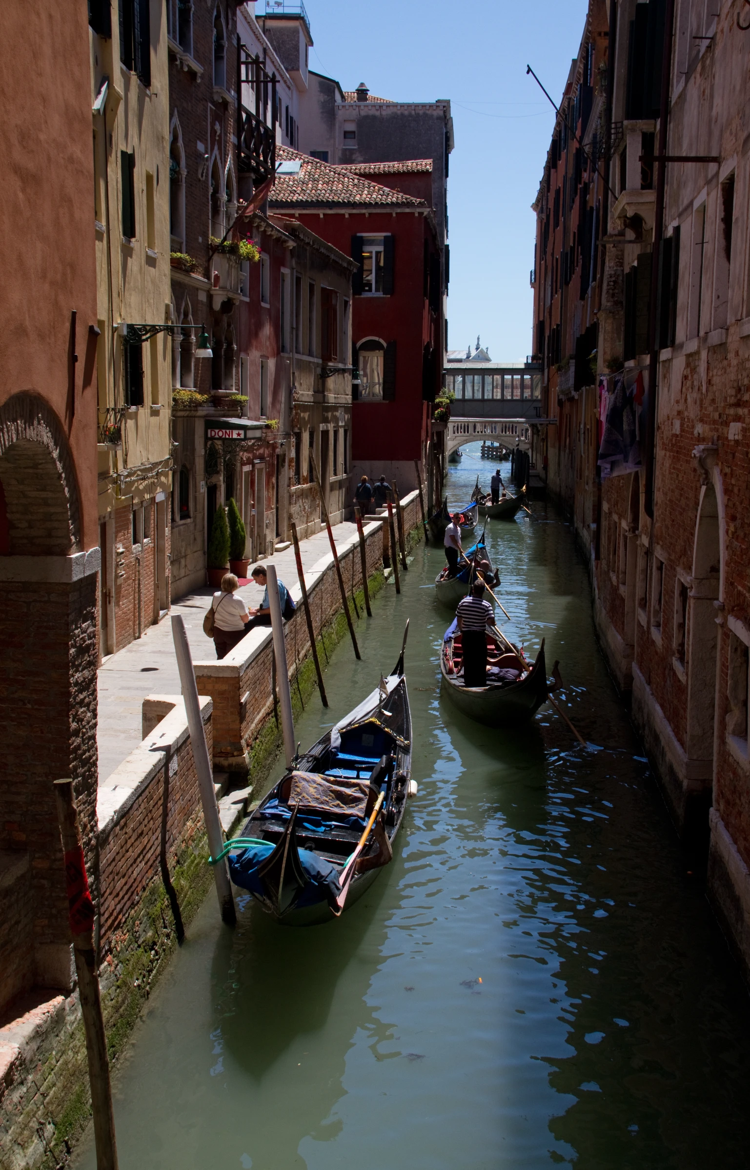 two boats with passengers parked near a small waterway in an urban setting