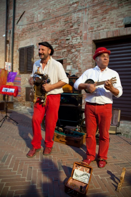 two men standing with instruments outside on the sidewalk