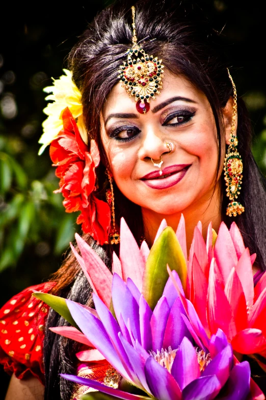 a woman wearing a makeup and head piece holding a large flower