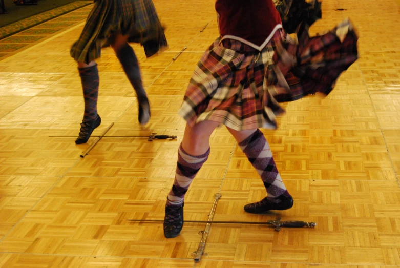 a woman wearing plaid and knee high socks dancing on a wood floor