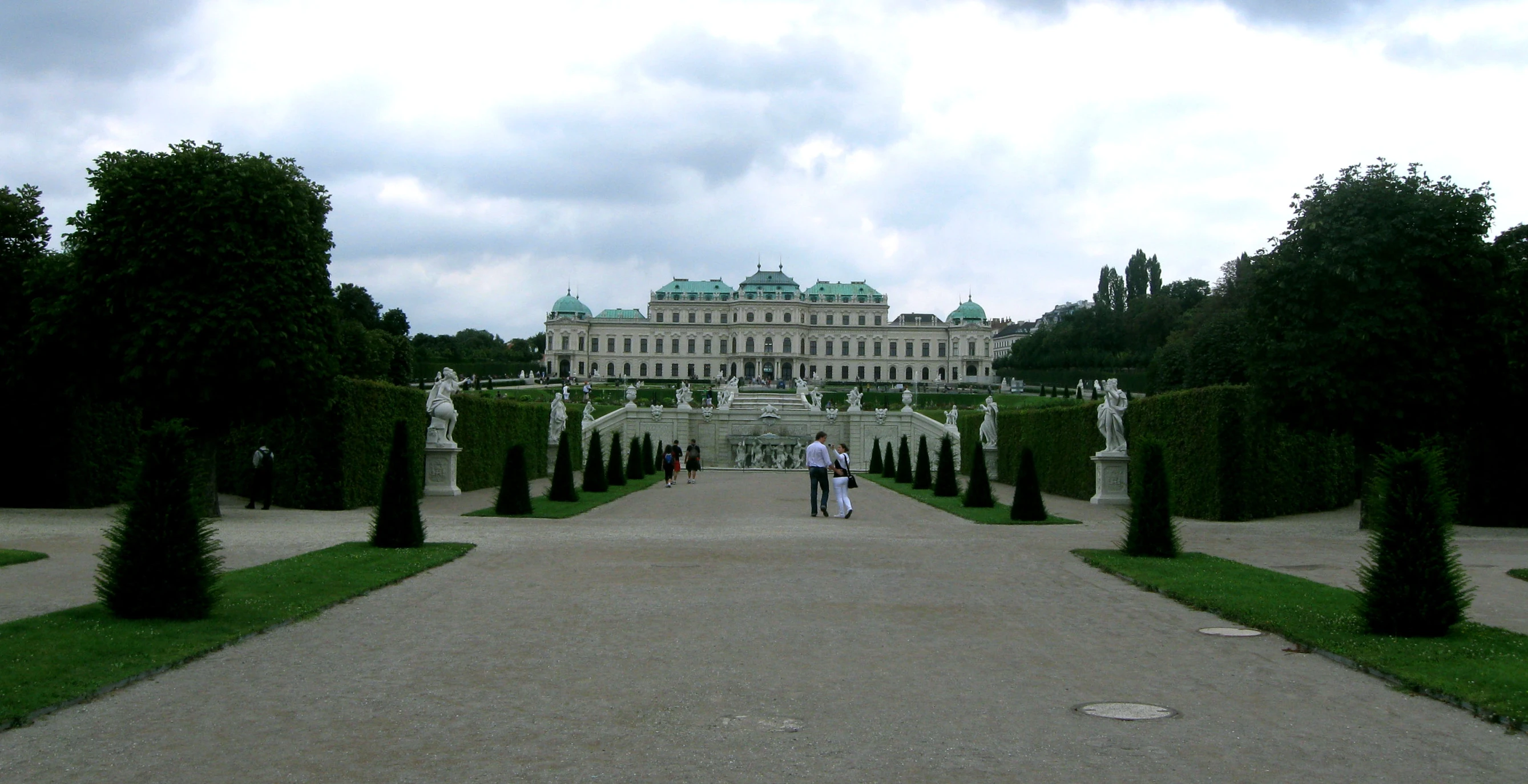 an ornate building with a large lawn near some tall trees