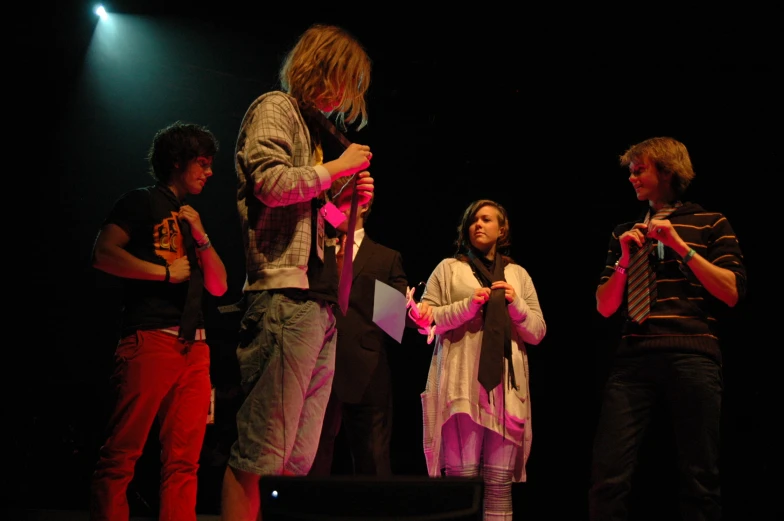 four people with their hands in their pockets are standing on stage