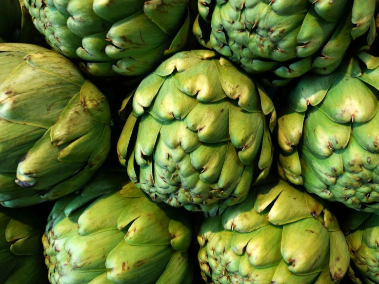 a large pile of green artichokes for sale