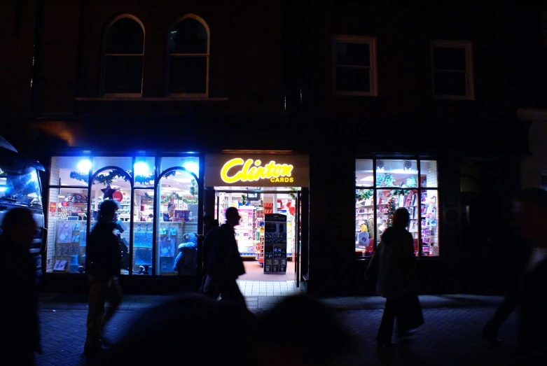 people walking by storefronts at night in a city