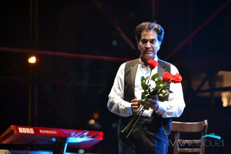 a man that is holding some red flowers