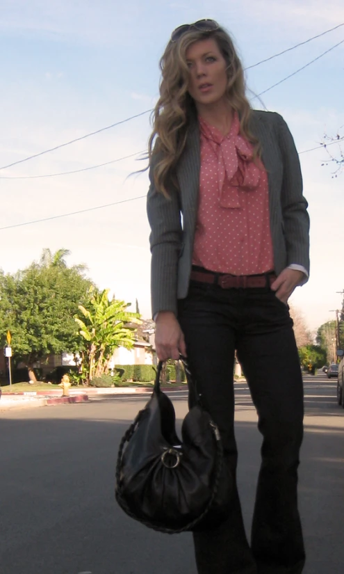 woman carrying large black purse while walking on road