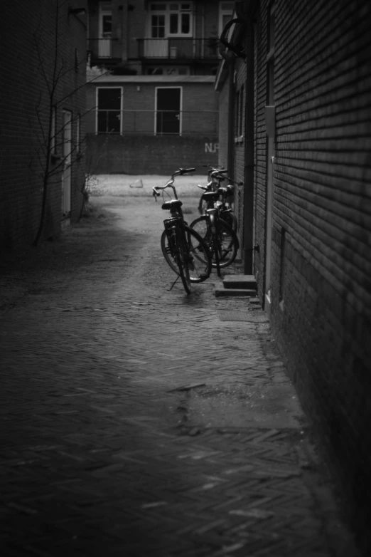 three bikes parked by the wall on a wet street