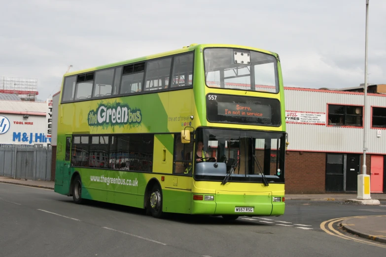 a green double decker bus driving down the street