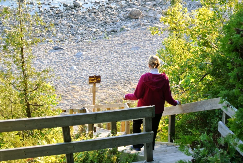 woman in red coat on bridge above a river