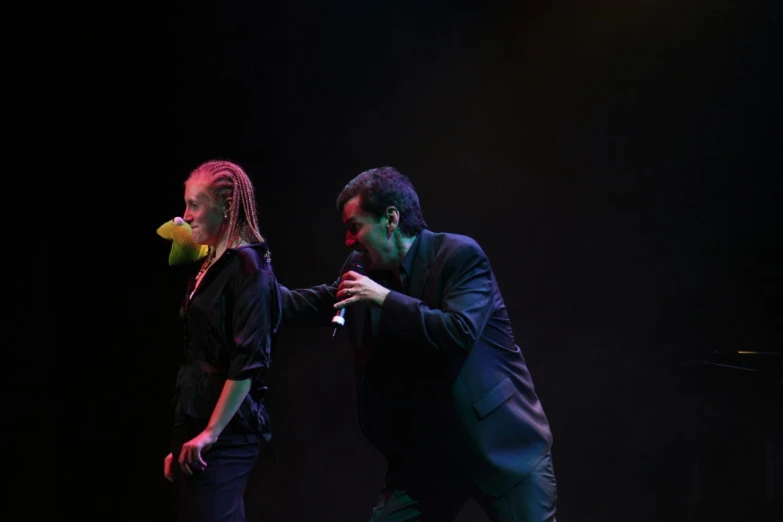 two people standing on a stage, one holding an object