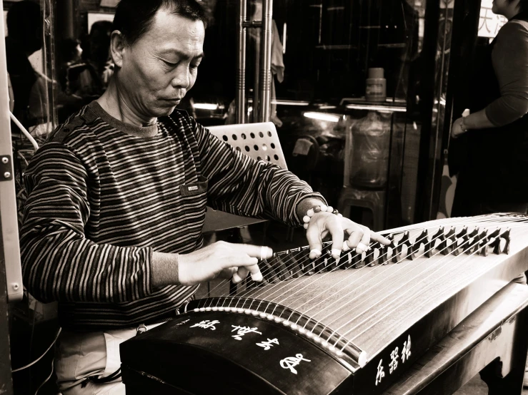 man sitting at a table playing an oriental music instrument