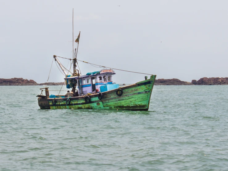 the green, weathered boat in the water is going to shore