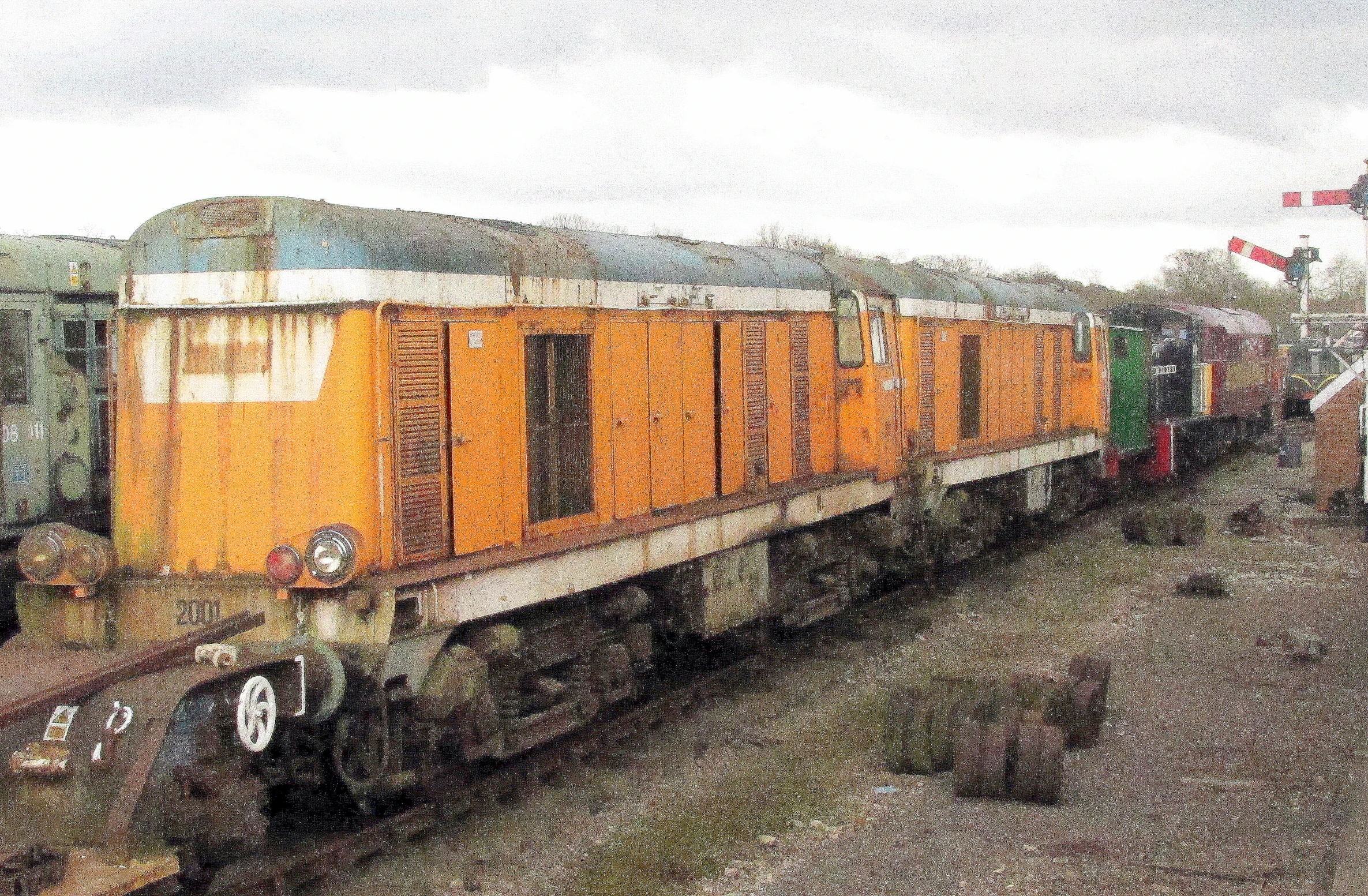 a yellow train sitting on the tracks in an enclosed lot