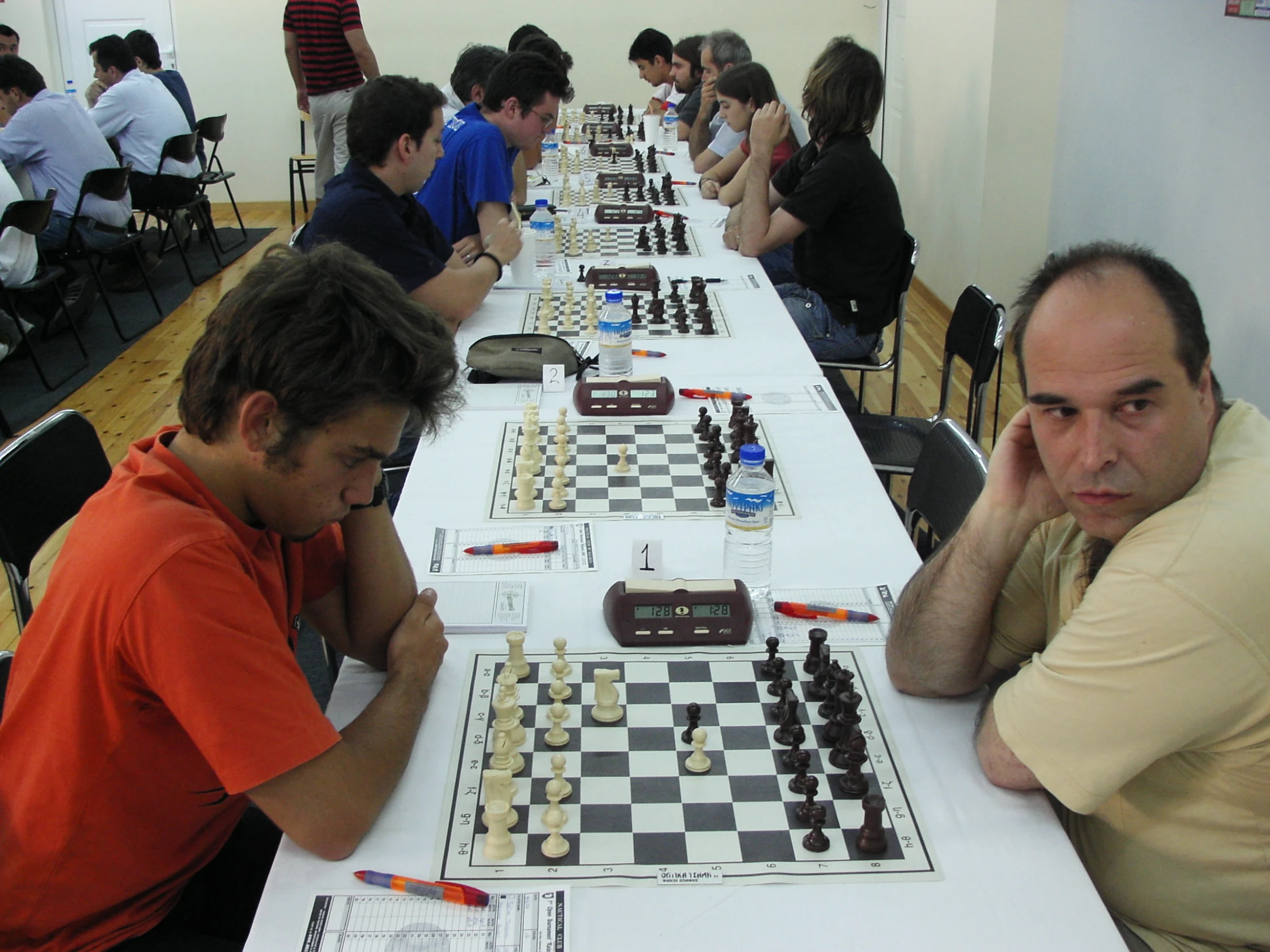 several men are playing chess at the long table