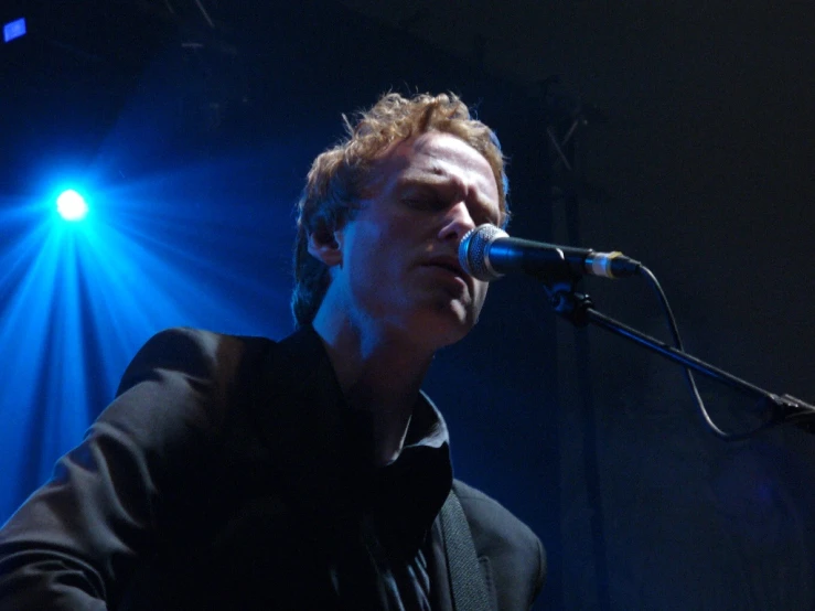 a man singing into a microphone with bright blue lights