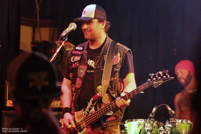 a man playing guitar and wearing a hat