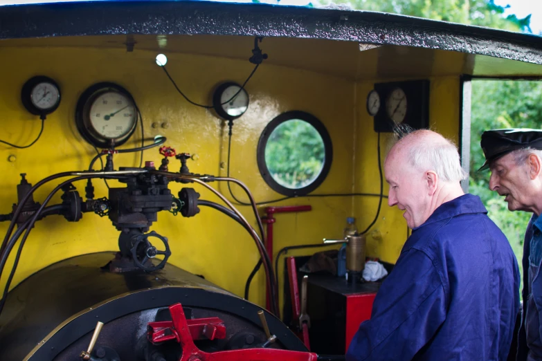 two men stand by a steam engine on display