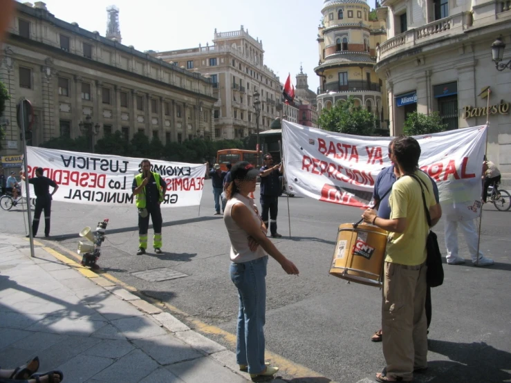 group of people holding signs standing on the side of the street