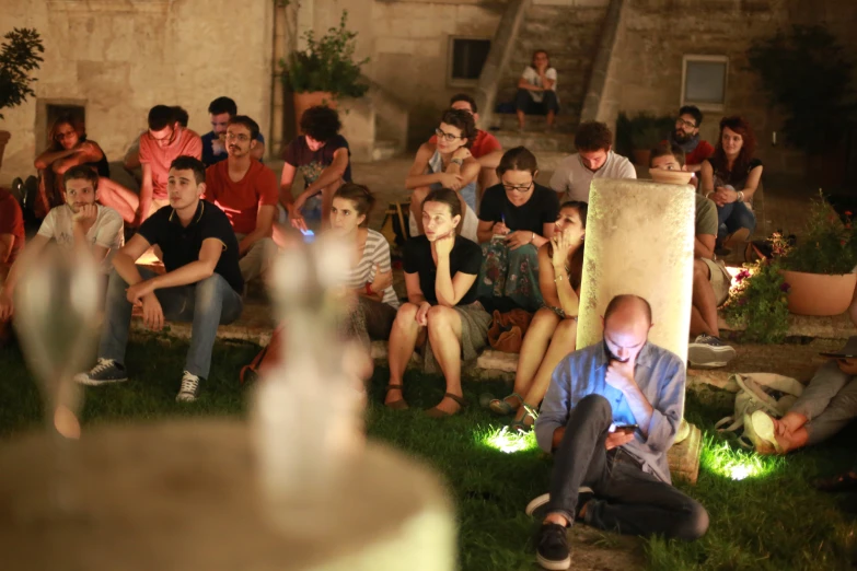 a crowd sitting on the ground and people standing on steps