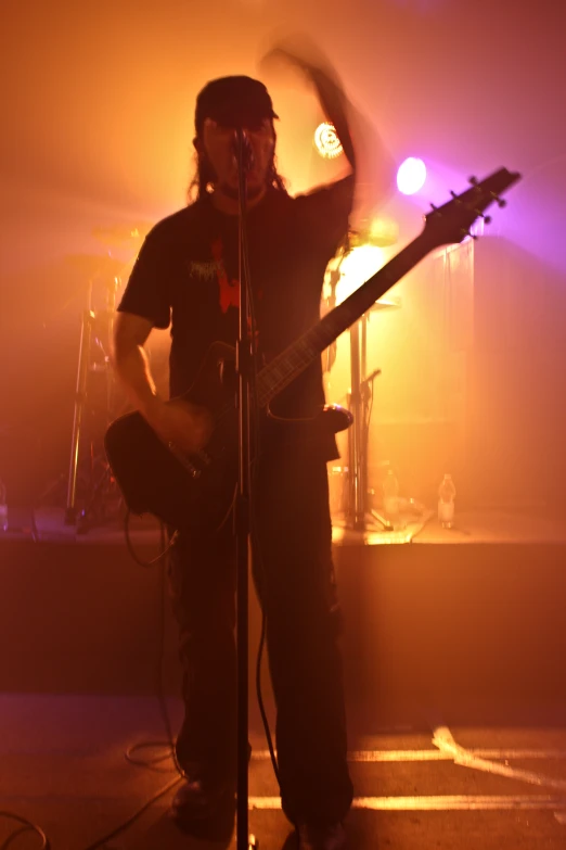 man singing into microphone and guitar in front of band