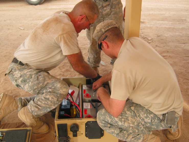 two men in uniform assemble electronics to use