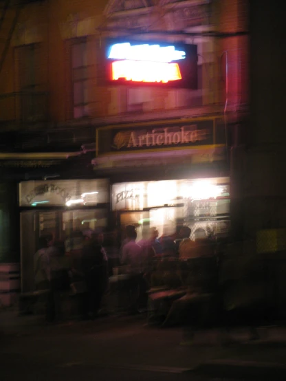 a group of people stand outside of a store at night