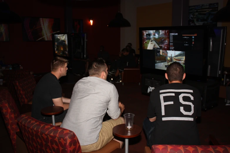 three men sitting and playing a game on tv