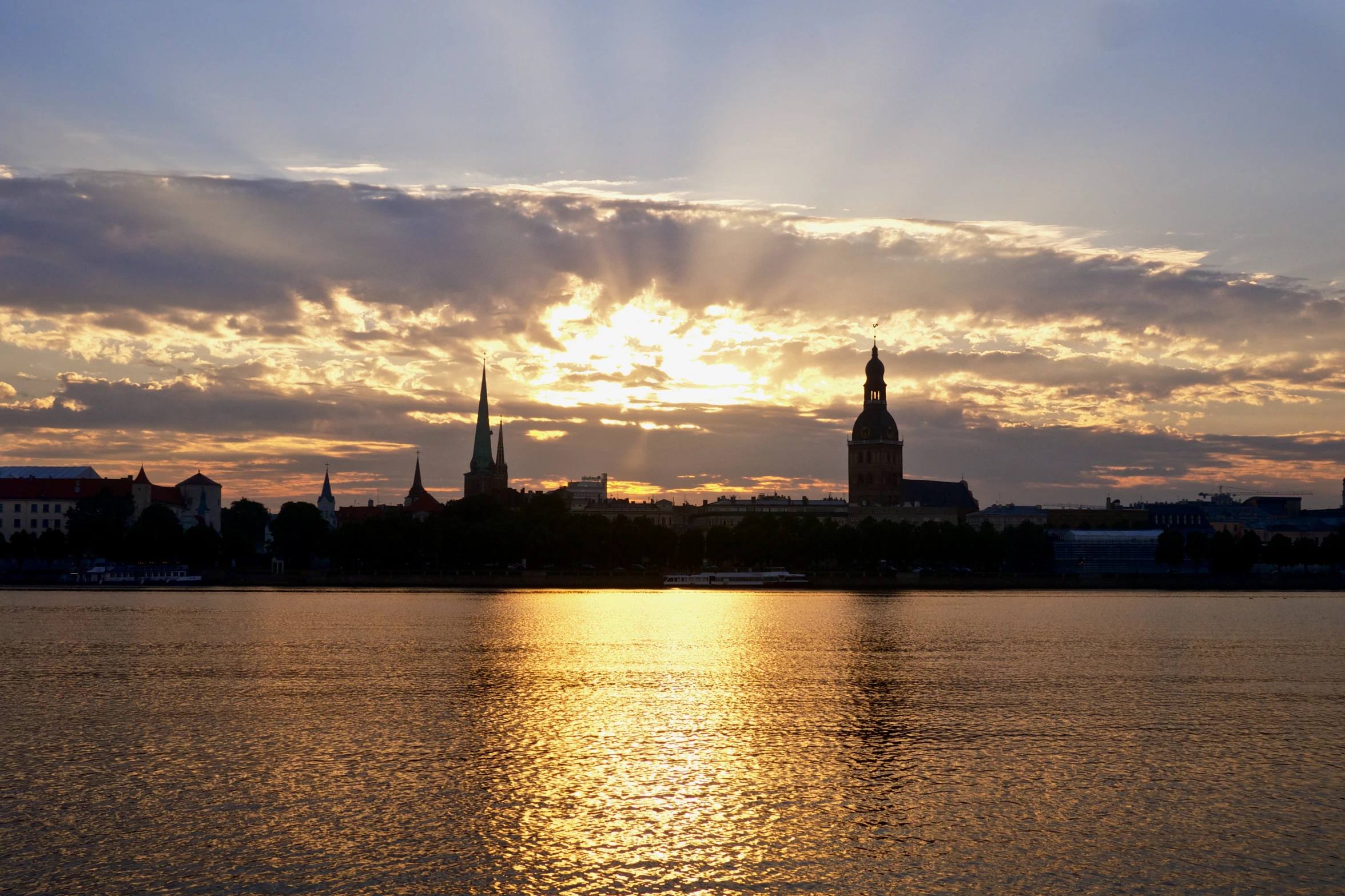 a beautiful sunset reflects in the water near a big city