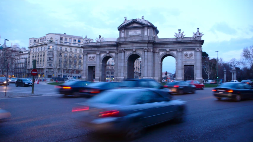 a city street with traffic passing under a arch