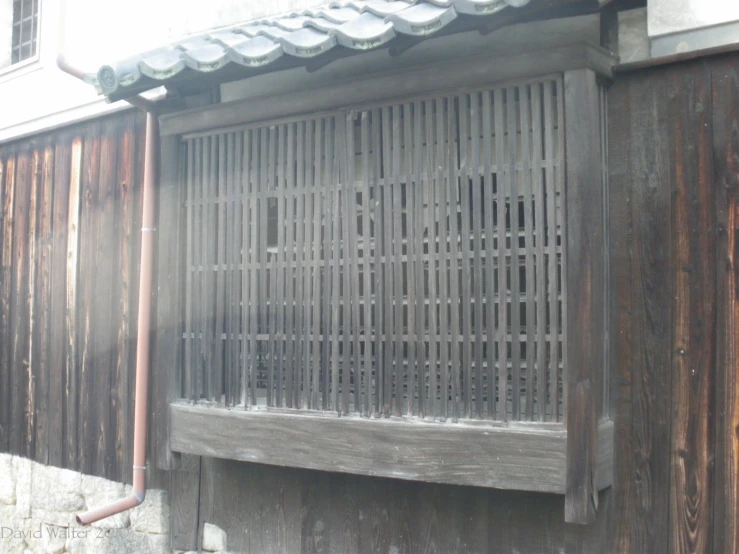 an old wooden wall and window with metal grates