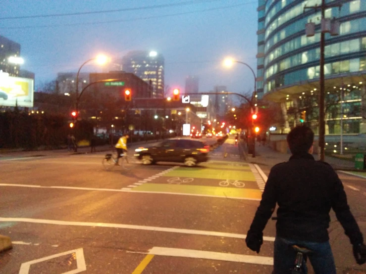 a city with traffic lights, buildings, people and a person on a bike