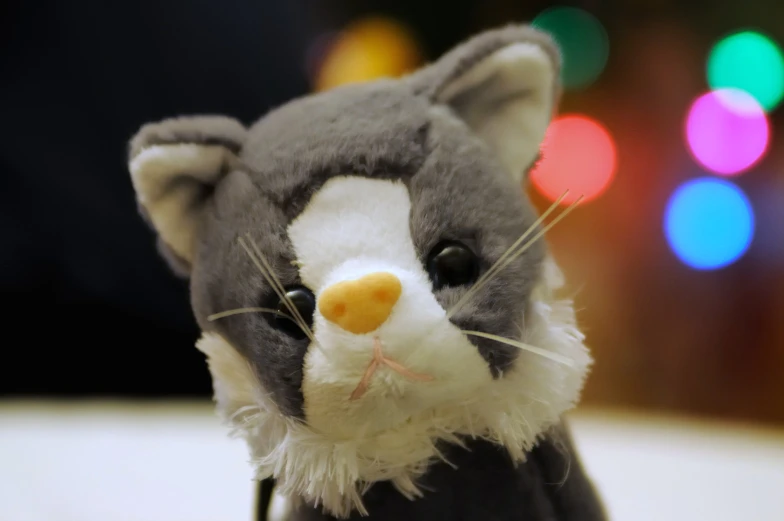 small stuffed animal mouse sitting in front of a background of lights