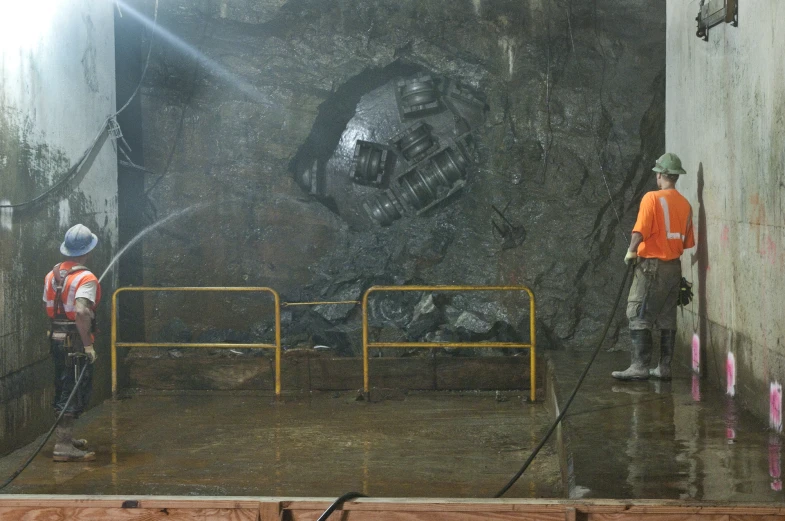 workers spray water on a large art work in a factory