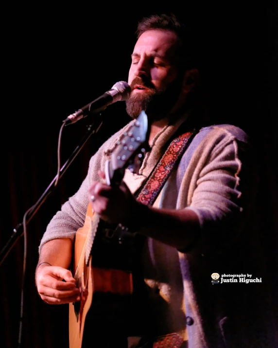 a man playing a guitar in front of a microphone