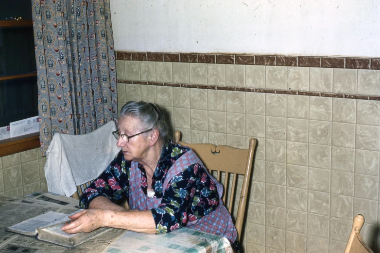 an older woman wearing glasses sitting at a table