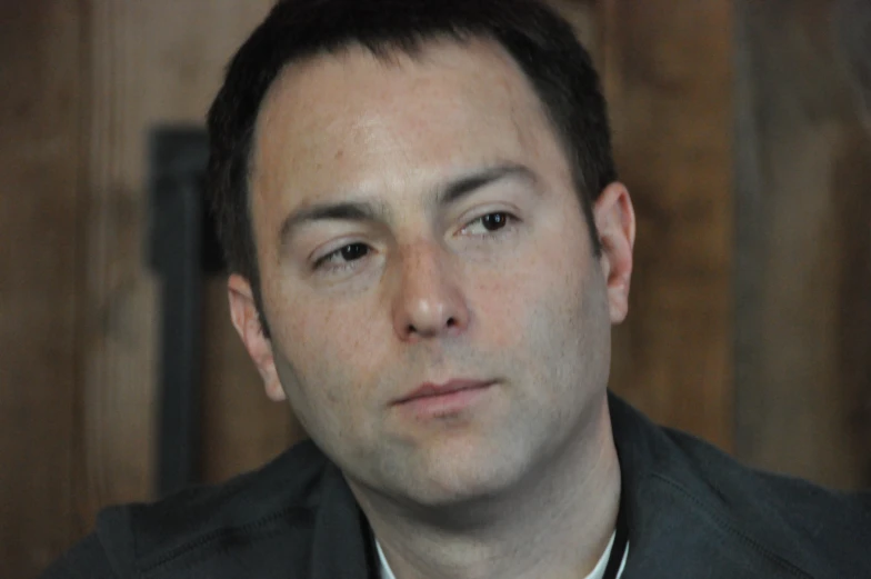 a man with short hair wearing a collared shirt and posing for the camera